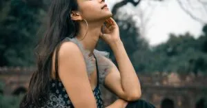 A young woman in a stylish outfit poses in a serene New Delhi park, showcasing grace and beauty.