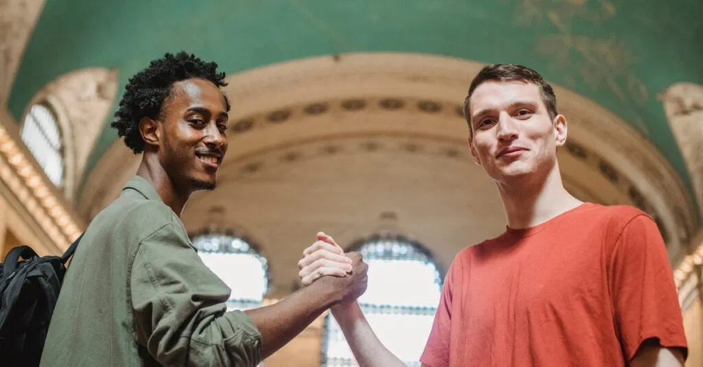 Bus Grand Central to Newark: 10 Smart Tips to Make Your Trip Easy 13 From below of positive young multiethnic male friends in casual clothes smiling and looking at camera while shaking hands in spacious aged arched building