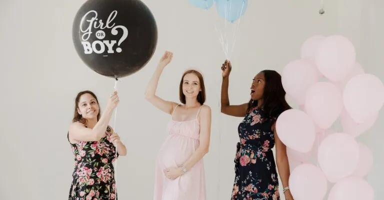 Three women celebrate at a gender reveal party with balloons, creating a fun and happy atmosphere.