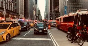 Dynamic scene of New York City traffic amid towering skyscrapers, vibrant urban life.