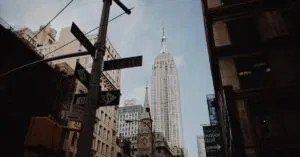 Low angle view of the Empire State Building amidst New York City's urban architecture and street signs.