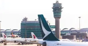 Airplane tailfin and control tower in view at a busy airport terminal.