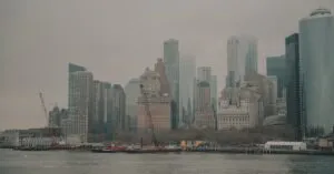 A foggy view of New York City's iconic skyline as seen from the Hudson River, highlighting its skyscrapers.