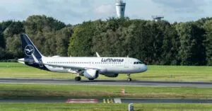 Lufthansa Airbus A320 taxiing at Hamburg Airport on a sunny day.