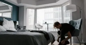 Contemporary hotel room with a man tying shoes in a bright Toronto setting.