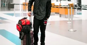 Man standing with luggage in a modern airport terminal, ready for travel.
