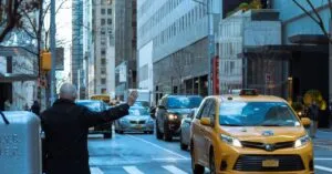 A man hailing a yellow taxi in bustling NYC street, capturing urban life.