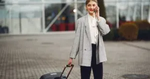 A sleek black JetBlack sedan waits at LaGuardia Airport’s Terminal B pickup zone, its driver holding a sign under a rainy Queens sky, ready for an affordable car service to LaGuardia in 2025.