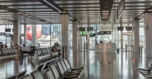 Spacious airport terminal with empty seating and a view of an airplane through large glass windows.
