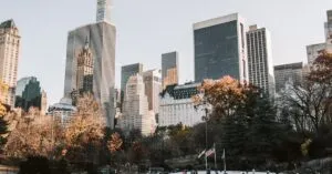 People enjoy ice skating at Central Park's Wollman Rink with NYC skyline in winter.