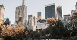 People enjoy ice skating at Central Park's Wollman Rink with NYC skyline in winter.