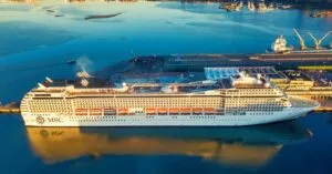 Aerial view of a cruise ship docked at a South African harbor with city skyline.