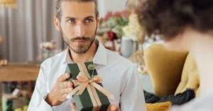 A thoughtful moment captured as a man presents a gift in a cozy indoor setting.