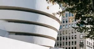 Exterior of museum modern and contemporary art with rounded walls located near residential building and green tree in city street