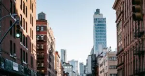 District of New York with aged residential buildings and modern commercial skyscrapers against cloudless blue sky