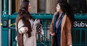 Side view of young stylish multiracial female friends in fashionable outfits standing on street and gossiping near subway station