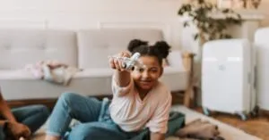 Young girl playing with a toy plane at home, sitting on the carpet.