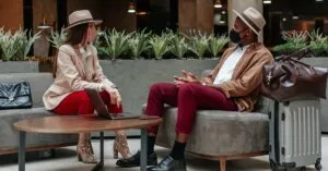 Caucasian woman and Black man meeting in hotel lobby wearing face masks.