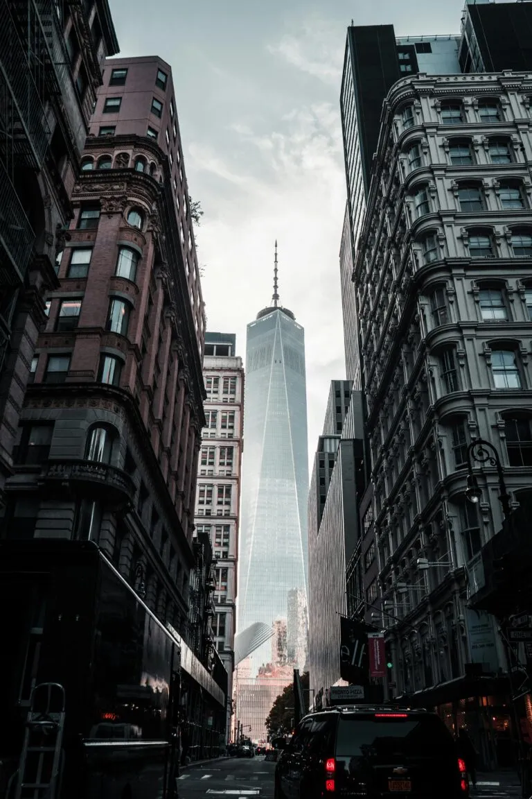 A stunning view of One World Trade Center framed by city buildings from a low angle.