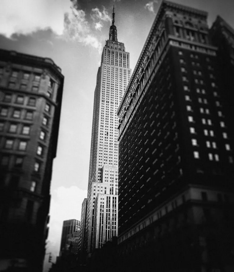 Dramatic black and white view of the Empire State Building amidst New York City skyscrapers.