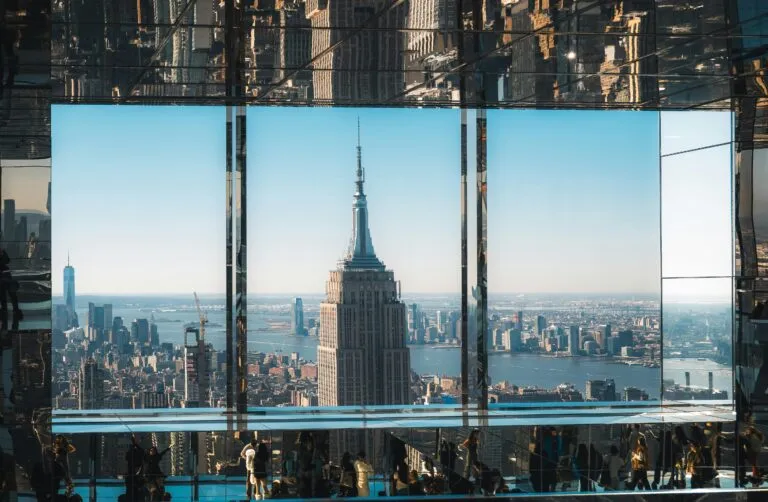 An aerial view of the Empire State Building through reflective glass, capturing New York City's iconic skyline.