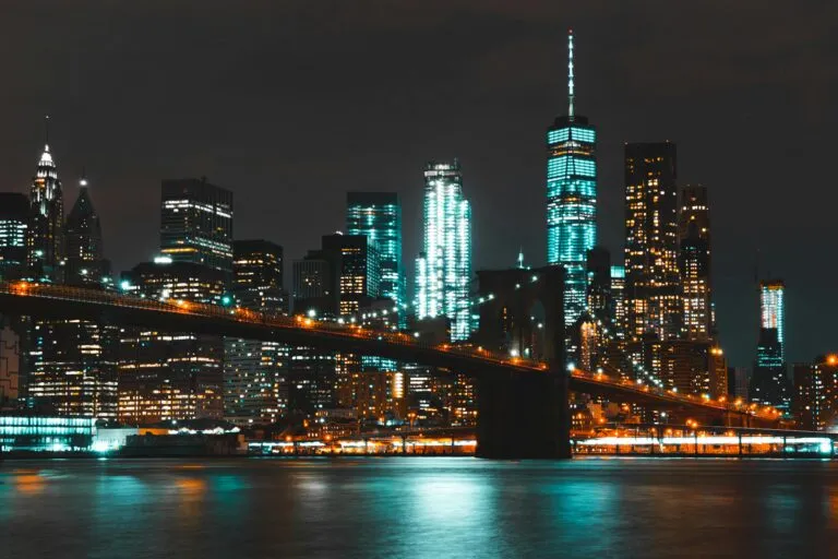 Captivating night skyline of New York City with Brooklyn Bridge and skyscraper reflections.