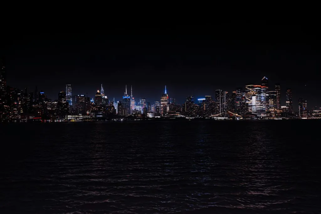 Breathtaking night view of the illuminated New York City skyline across the water.